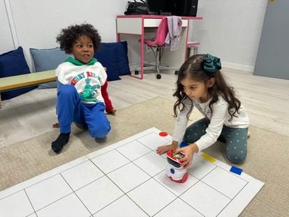 Dos alumnos de cuatro y cinco años del CEIP Gumersindo Azcárate (León) en la Sala del Futuro del centro programan un robot para que siga un camino determinado a lo largo de la alfombra cuadriculada.